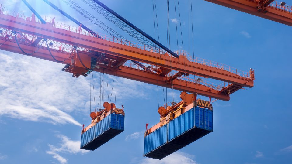 Maskiner lastar containrar för båttransport