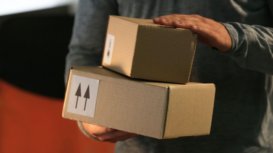 Man som håller i paket som väntar på att bli fraktade med flyg