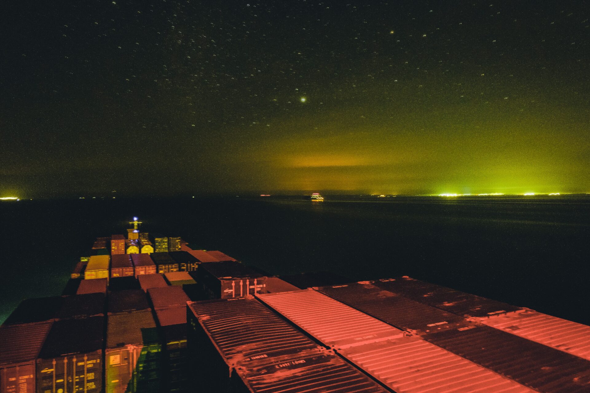 Containrar med gods på ett fartyg, även kallat båtfrakt alternativt sjöfrakt, lämnar hamnen kvällstid