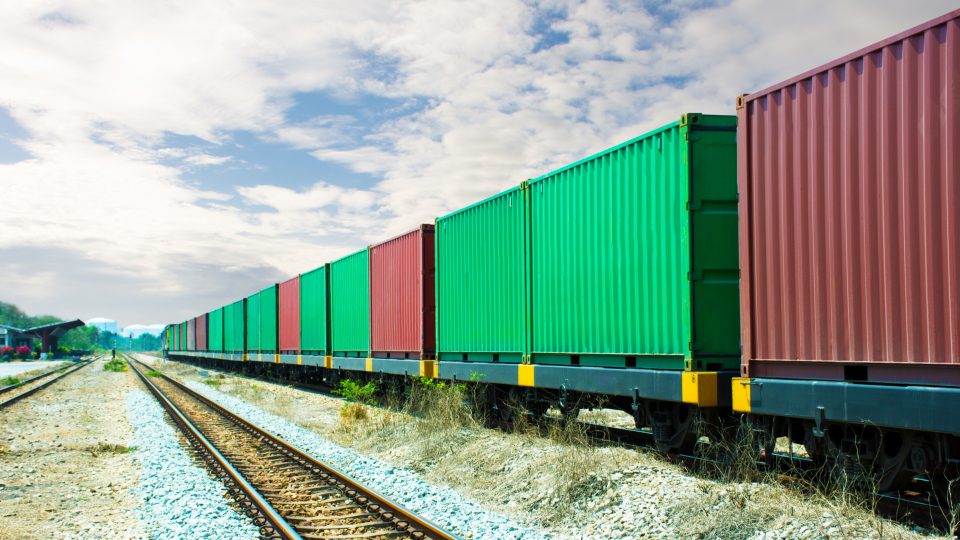 Tågtransport med containrar i rött och grönt.